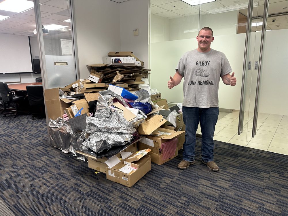 Gilroy Junk Removal crew member with a pile of office boxes and debris cleared from a commercial space